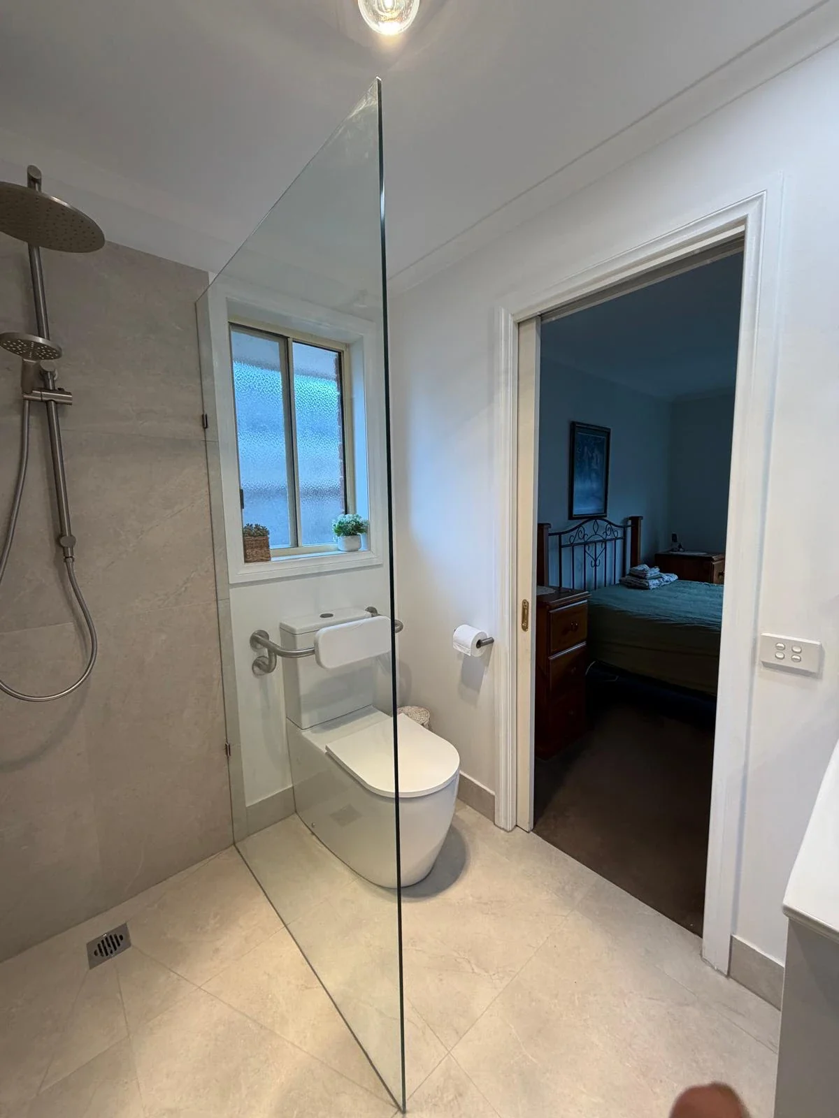 Completed bathroom with a frameless glass shower screen, brushed tapware and a back-to-wall toilet
